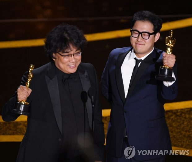 Bong Joon-ho (L) and Han Jin-won accept the Best Original Screenplay award for "Parasite" during the 92nd Oscars at the Dolby Theatre in Los Angeles on Feb. 9 in this photo released by AFP. (Yonhap)
