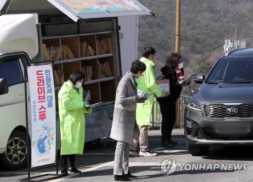 Officials of the Busan Metropolitan Library lend books to citizens in a drive-thru (Yonhap)