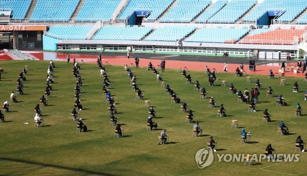This photo, taken on April 4, 2020, shows people taking a company entrance test at an outdoor stadium in Ansan, outside of Seoul. Applicants were seated five meters apart from each other. (Yonhap)