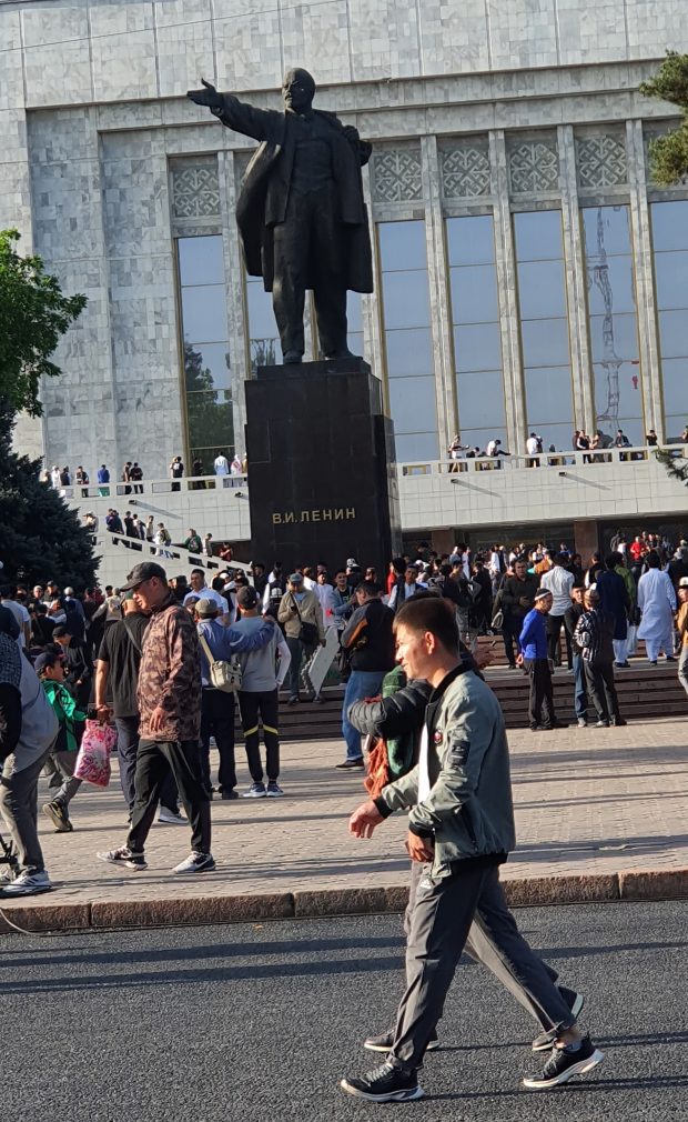 People walk past the statue of Lenin