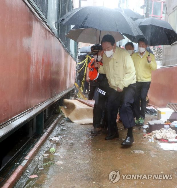 President Yoon Suk-yeol (front) inspects a submerged semi-basement home in Seoul's Gwanak Ward on Aug. 9, 2022, where three family members were stranded and later found dead after heavy rainfall began pounding Seoul and parts of central South Korea the previous day. (Yonhap)